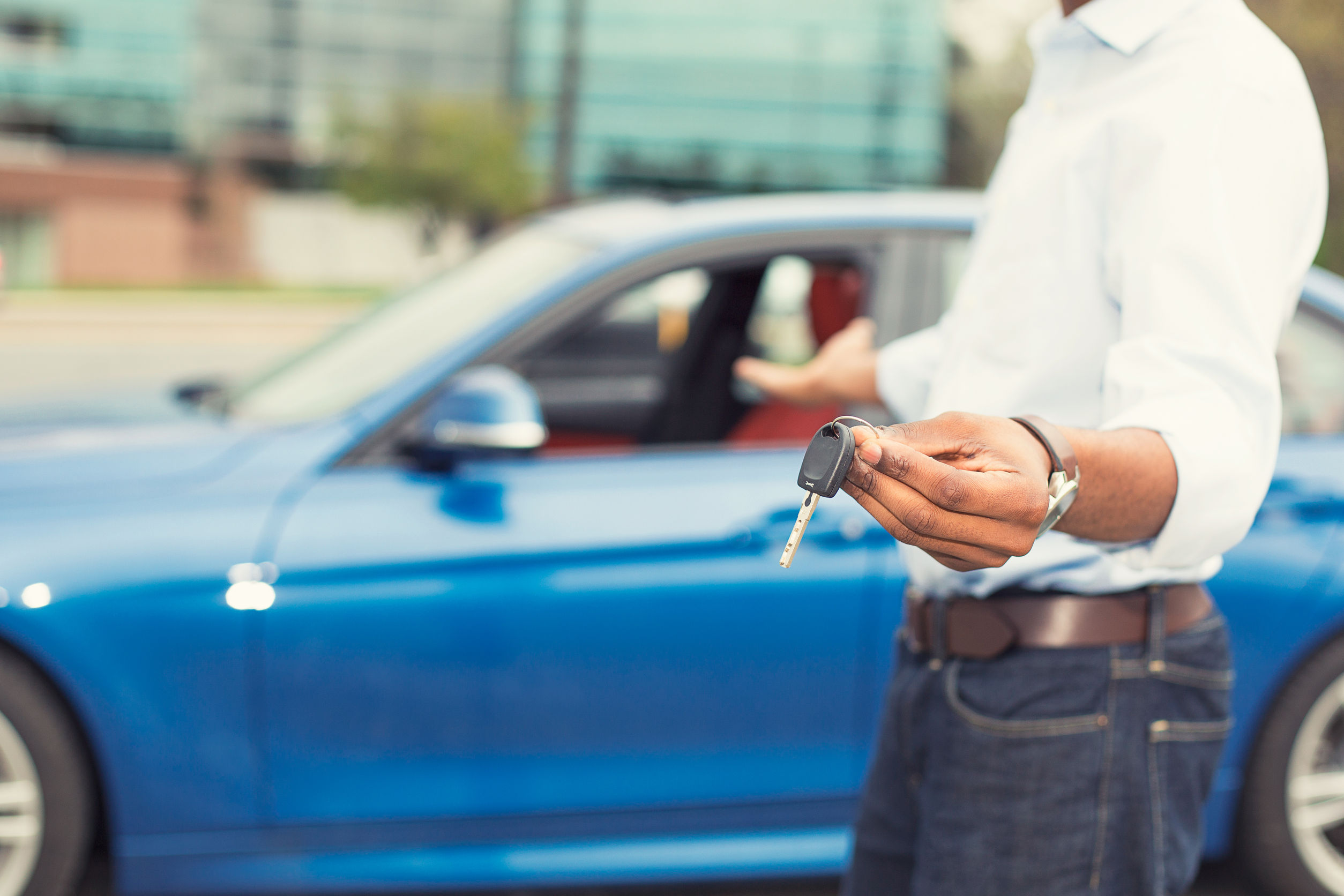 40416365 - male hand holding car keys offering new blue car on background